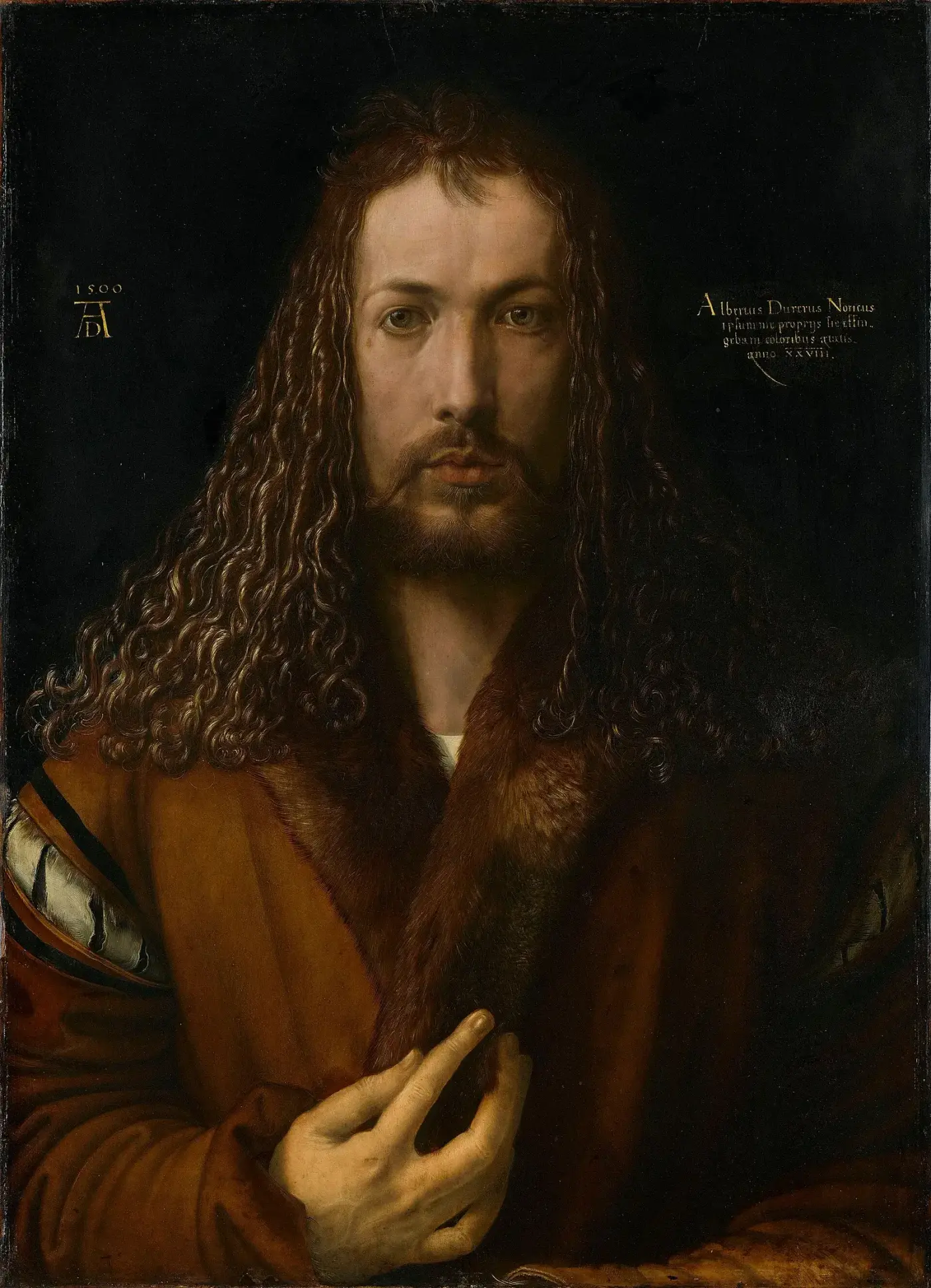 Autorretrato frontal de medio cuerpo sobre fondo oscuro: melena larga y simétrica, abrigo de piel, la mano derecha alzada ante el pecho.