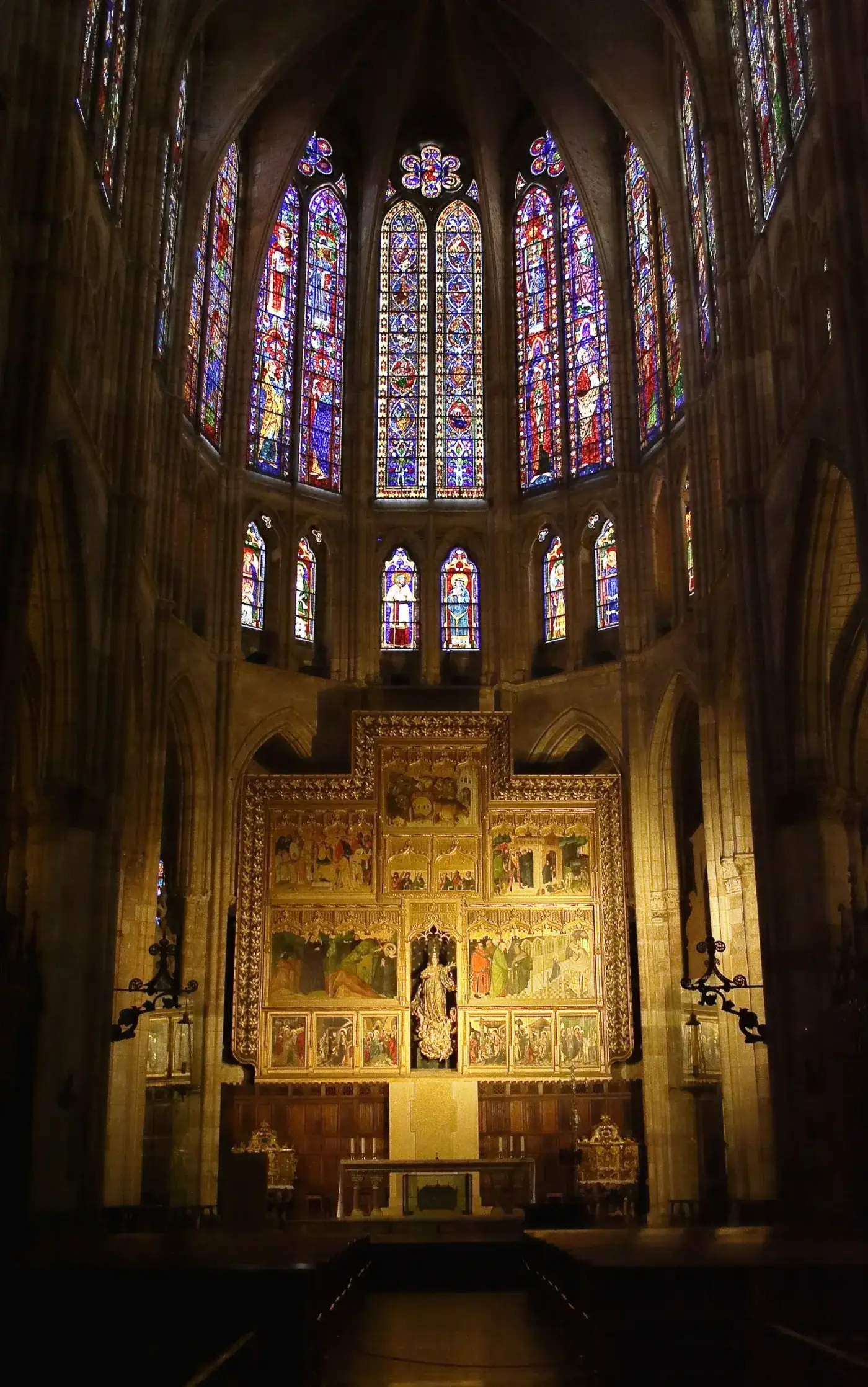 Muro gótico casi enteramente calado, con altos ventanales de vidriera coloreada separados por finos maineles de piedra.