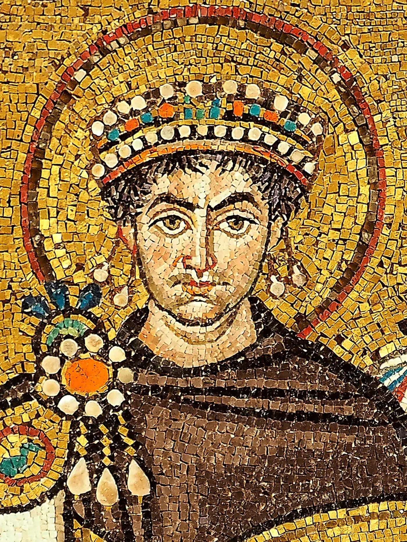 Mosaico bizantino con el emperador Justiniano en el centro, con nimbo y manto púrpura, rodeado de clérigos, cortesanos y soldados, todos de frente y sobre fondo dorado.